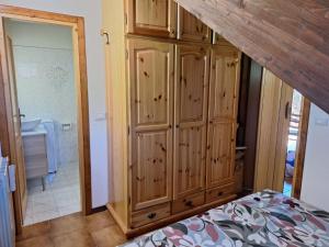 a bedroom with a large wooden cabinet next to a bathroom at Appartamento Bellavista in Pievepelago
