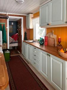 a kitchen with white cabinets and a room with a bed at Charming Cabin At The Foot Of The Mountain in Jordet