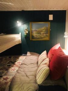 a bed with pillows in a room with a painting at Charming Cabin At The Foot Of The Mountain in Jordet