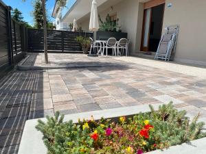 un patio con flores, mesa y sillas en Casa Eva, en Bibione