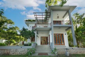 a white house with a balcony and stairs at Villa Sathkara in Tangalle