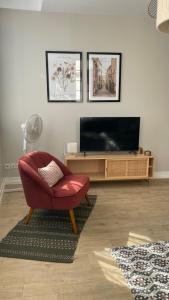 a living room with a red chair and a television at L' Harmonie in Périgueux
