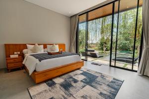 a bedroom with a bed and a large window at Merica Luxury Villa Ubud in Gianyar