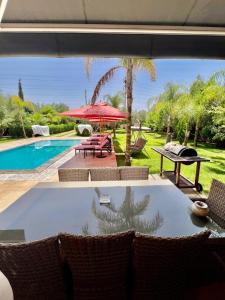 a swimming pool with a table and a red umbrella at Villa privée in Taazout +7 photos