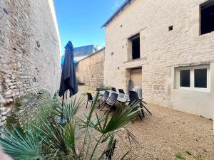 a group of chairs and an umbrella next to a building at La parenthèse Chic & Cosy - 8 min du Futuroscope ! in Saint-Georges-lès-Baillargeaux