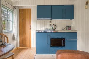 cocina azul con fregadero y microondas en Bluebell Lodge, Lake District, en Coniston