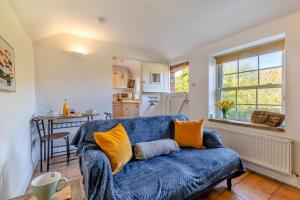 a living room with a blue couch and a kitchen at Poppy Cottage in Stiffkey