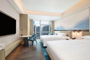 a hotel room with two beds and a flat screen tv at Courtyard by Marriott Zhuhai in Zhuhai +31 photos