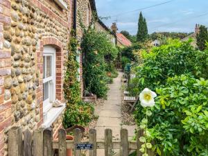 a garden with a fence and a house at Poppy Cottage in Stiffkey