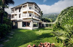 un grand bâtiment blanc avec une cour verdoyante dans l'établissement Hotel Lido La Perla Nera, à Stresa