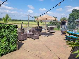 a patio with a table and chairs and an umbrella at Het Atelier Huis - Geschikt tot 8 personen in Maasbommel