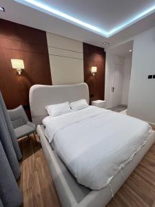 una camera da letto con un grande letto bianco e una sedia di شقــة فخمـــة a Shaqra