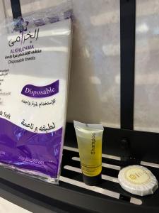 uno scaffale con un contenitore di plastica e una bottiglia di mascara di شقــة فخمـــة a Shaqra