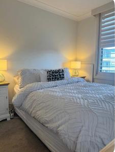 1 dormitorio blanco con 1 cama grande y 2 lámparas en Rocky Beach unit, en Port Macquarie