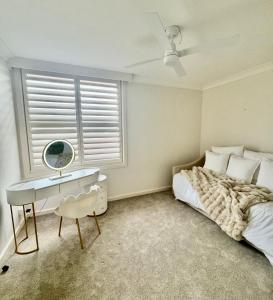 Un dormitorio con una cama, un escritorio y un espejo. en Rocky Beach unit, en Port Macquarie
