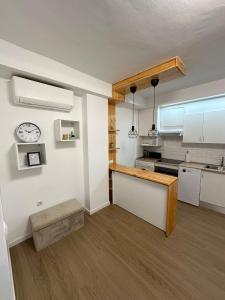 a kitchen with white cabinets and a clock on the wall at Apartamentos JM - Sea & Sun in Roquetas de Mar