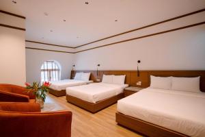 a hotel room with two beds and a chair at Toàn Cầu Hotel Quảng Bình in Dong Hoi +64 photos