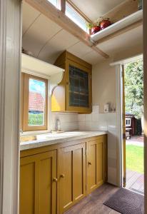 a kitchen with yellow cabinets and a window at Sfeervolle, historische woonwagen en extra studio in ruime tuin in Rohel