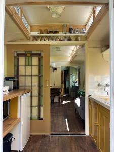 a kitchen with a view of a living room at Sfeervolle, historische woonwagen en extra studio in ruime tuin in Rohel