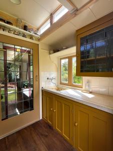 a kitchen with yellow cabinets and a sink at Sfeervolle, historische woonwagen en extra studio in ruime tuin in Rohel +55 photos
