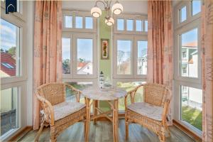 a dining room with a table and chairs and windows at Ferienwohnung Koralle in Ostseebad Koserow