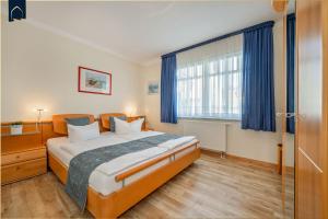 a bedroom with a large bed with blue curtains at Ferienwohnung Koralle in Ostseebad Koserow