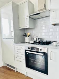 a kitchen with white cabinets and a stove top oven at Gorgeous two bedroom luxury Apartment sleeps 6 in Brentwood