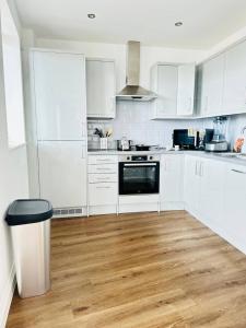 a white kitchen with wooden floors and white cabinets at Gorgeous two bedroom luxury Apartment sleeps 6 in Brentwood +5 photos