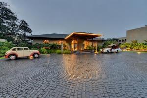 The Fern Vishranta Resort, Kamrej-Surat, Series by Marriott في سورات: سيارتان قديمتان متوقفتين امام مبنى