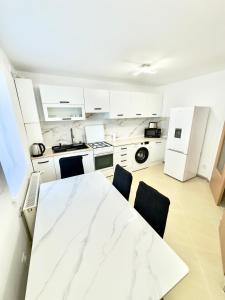 a kitchen with white cabinets and a table and chairs at Medias Apartament in Mediaş