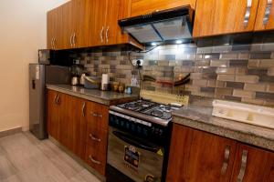 a kitchen with wooden cabinets and a stove top oven at Your Kigali Base a 2 Bedroom with Kitchen and Private Parking in Kigali