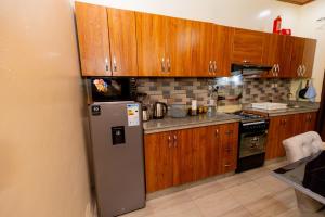 a kitchen with wooden cabinets and a refrigerator at Your Kigali Base a 2 Bedroom with Kitchen and Private Parking in Kigali