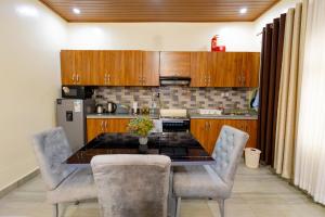 a kitchen with wooden cabinets and a table and chairs at Your Kigali Base a 2 Bedroom with Kitchen and Private Parking in Kigali