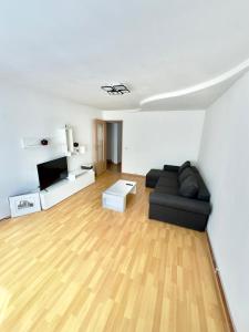 a living room with a black couch and a wooden floor at Medias Apartment in Mediaş