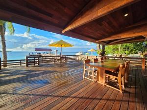 a wooden deck with a table and chairs and the ocean at Andau Dive Resort Raja Ampat in Tapokreng