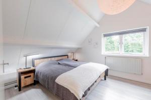 a white bedroom with a bed and a window at Doggersbank 16 - Noordzeepark Ouddorp in Ouddorp