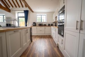 cocina grande con armarios blancos y suelo de madera en Rookery Park Barn, en Carlton Colville