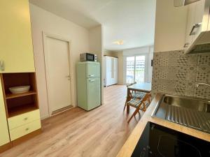 a kitchen with a green refrigerator and a table at Bright studio only 320mt from the sea in Porto Santa Margherita di Caorle