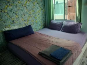 a bed with blue pillows and a blanket on it at Canaan in Kanchanaburi City