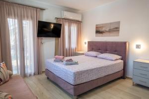 a bedroom with a bed and a flat screen tv at Myrina Retreat - Aegean in Mirina