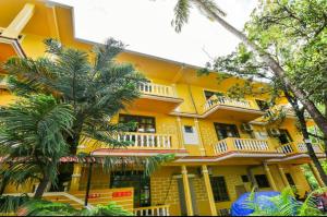 a yellow building with palm trees in front of it at maya guest house in Calangute