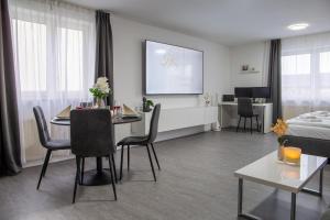 a living room with a table with chairs and a screen at Holiday&Stay, Apartment Relax, Küche, 85Zoll TV, WLAN in Weingarten