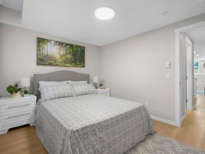 YYCにあるExquisite 1-Bdr Condo Aptの白いベッドルーム(ベッド1台付)が備わります。壁には絵画が飾られています。
