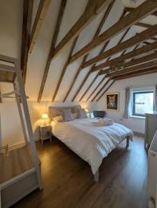 a bedroom with a large white bed and wooden ceilings at Tomnauld Farm Wellness Cottage in Pitlochry