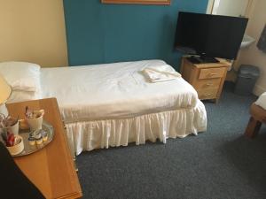 une chambre d'hôtel avec un lit et une télévision à écran plat dans l'établissement Four Seasons Budget, à Aberystwyth 4 autres photos