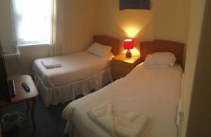 une chambre d'hôtel avec deux lits et une lampe rouge dans l'établissement Four Seasons Budget, à Aberystwyth