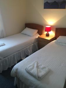 - 2 lits dans une chambre avec une lampe sur une table de nuit dans l'établissement Four Seasons Budget, à Aberystwyth