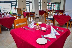 a dining room with red tables with plates and napkins at The Dalton Grand Hotel in Murangʼa