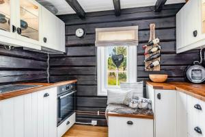 eine Küche mit weißen Schränken und einer schwarzen Wand in der Unterkunft Family-Friendly Log Cabin With Panoramic View in Østby