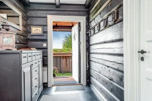 eine Tür, die zu einer Küche mit einer Holzwand führt in der Unterkunft Family-Friendly Log Cabin With Panoramic View in Østby + 17 Fotos